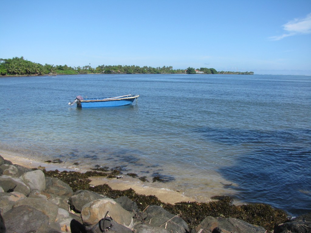 A small blue boat sits on the shore in Upolu, Samoa.